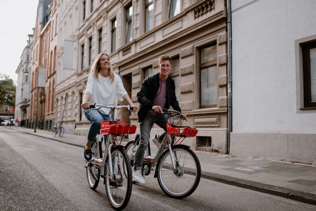 Woman and man ride their Call a Bike bicycles through the city center