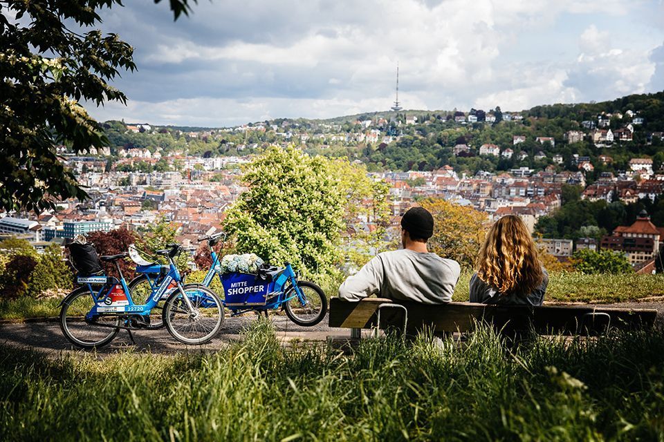 Couple on a park bench next to blue bike and cargo pedelec