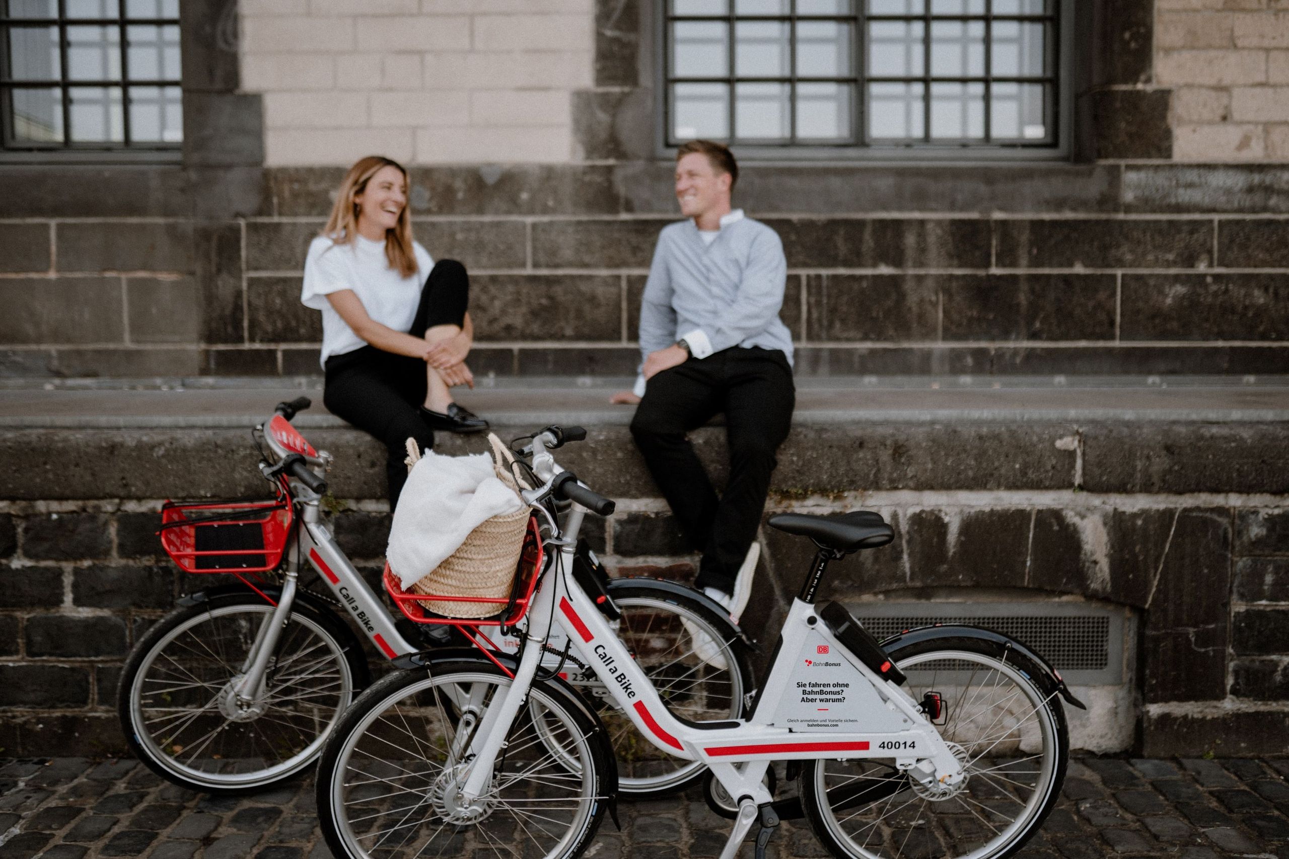 Eine Frau und ein Mann sitzen auf einer Mauer, vor ihnen stehen zwei Call a Bike-Leihräder