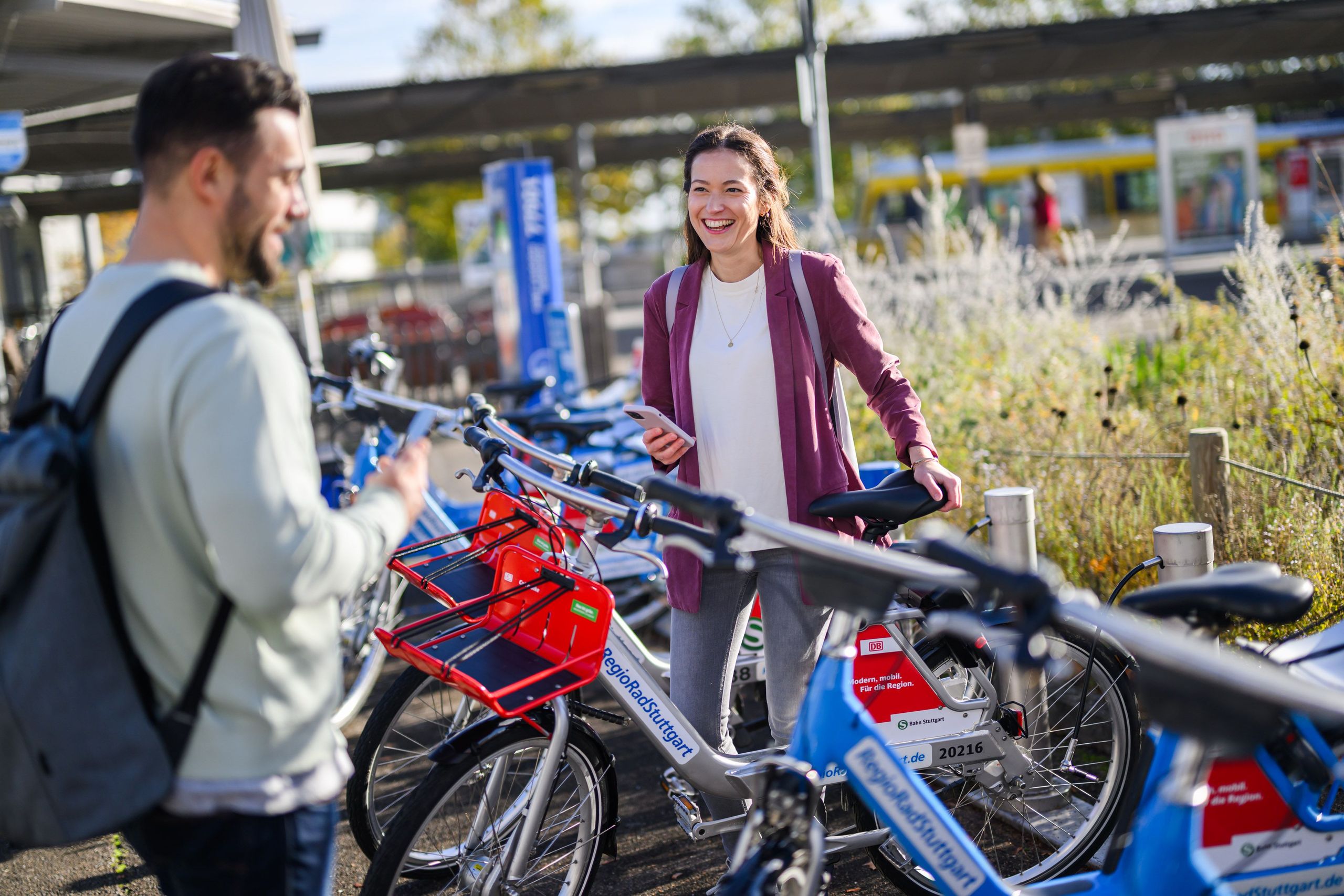 Two people standing in front of a train station and renting bikes